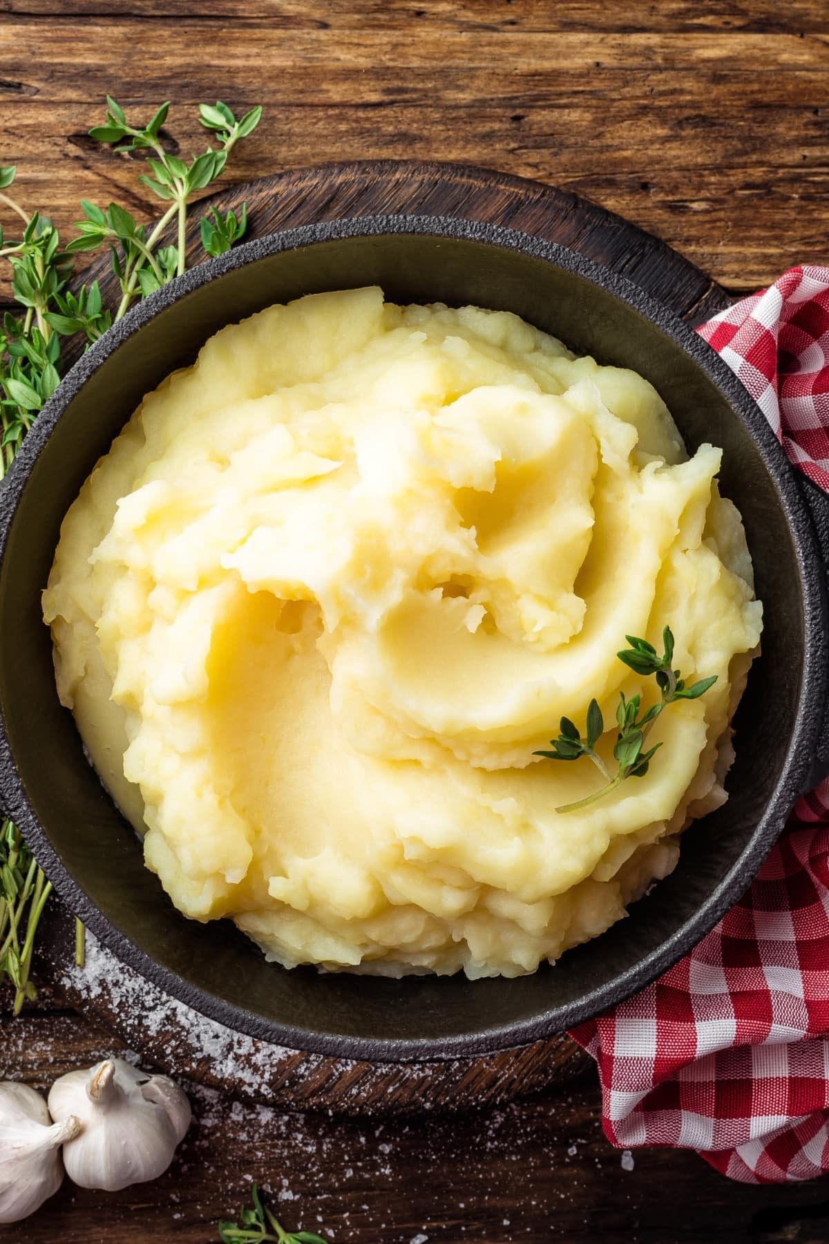 a bowl of creamy mashed potatoes garnished with a sprig of thyme