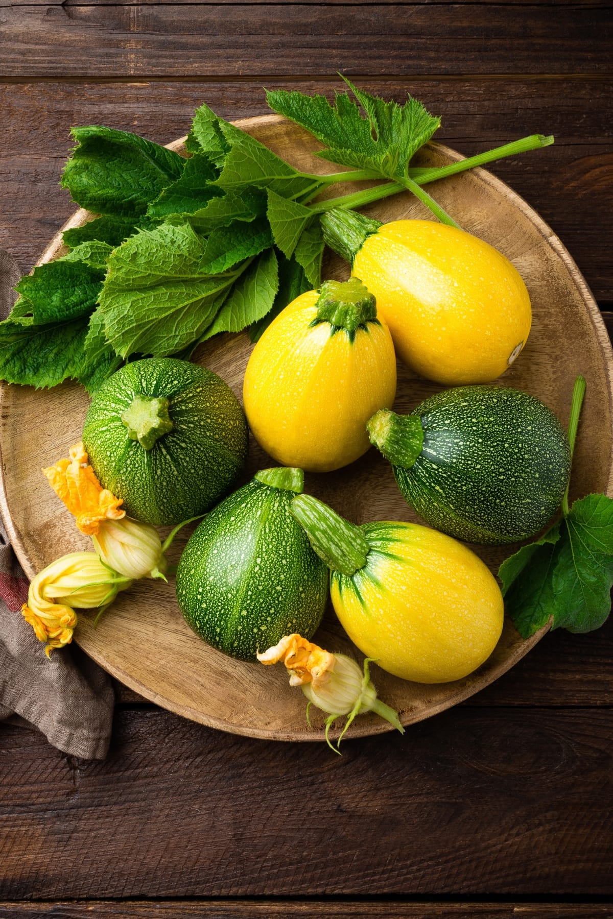 Fresh zucchini and yellow summer squash neatly arranged on a wooden table