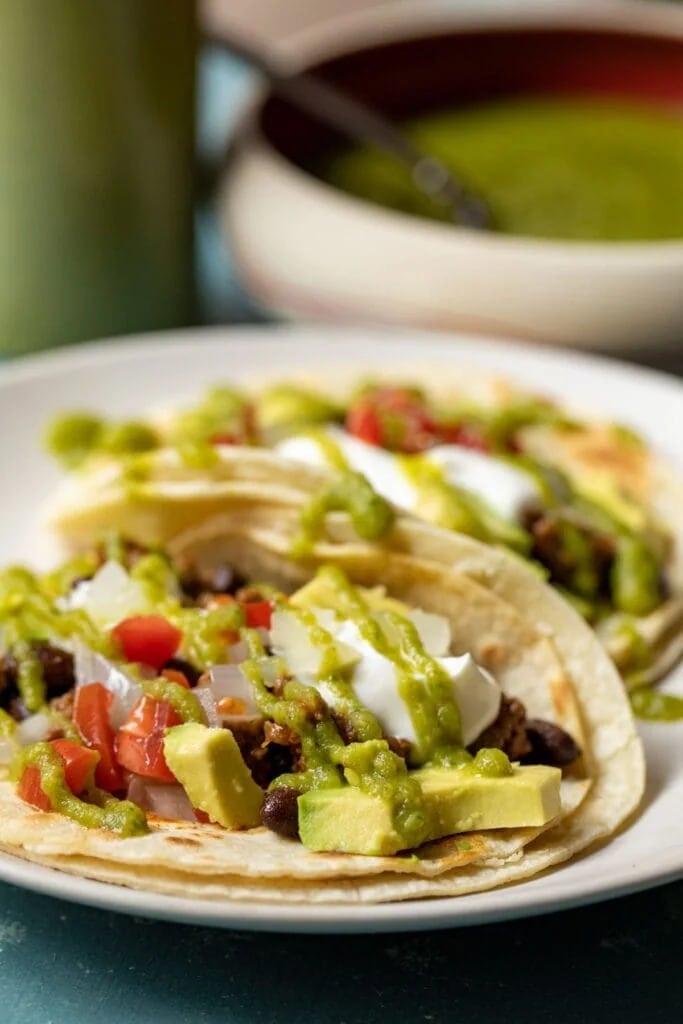 Homemade tacos with avocado, tomatoes, cream and green taco sauce