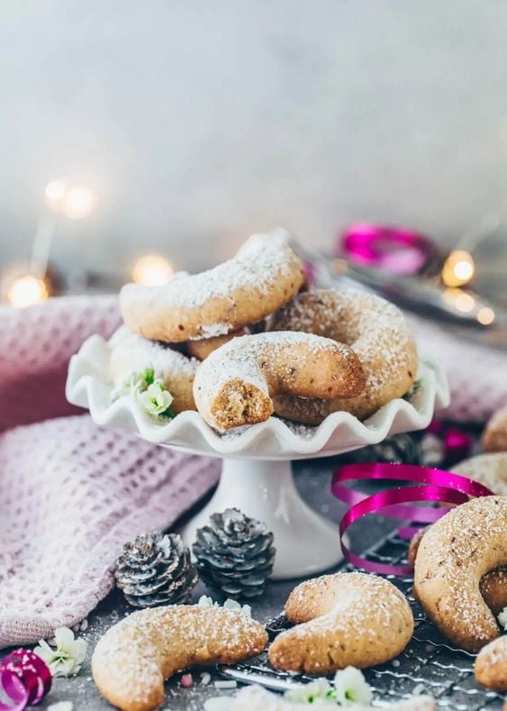 Powdered sugar coated crescent shape cookies on a cake tray. 