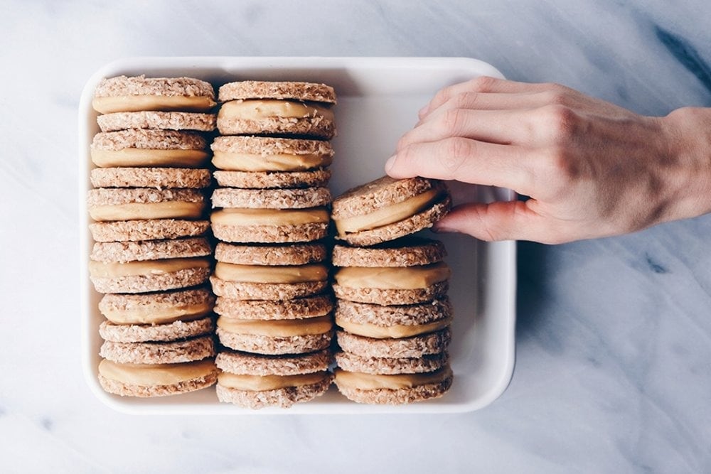 Hand picking gingerbread sandwich with cashews with nut milk filling. 