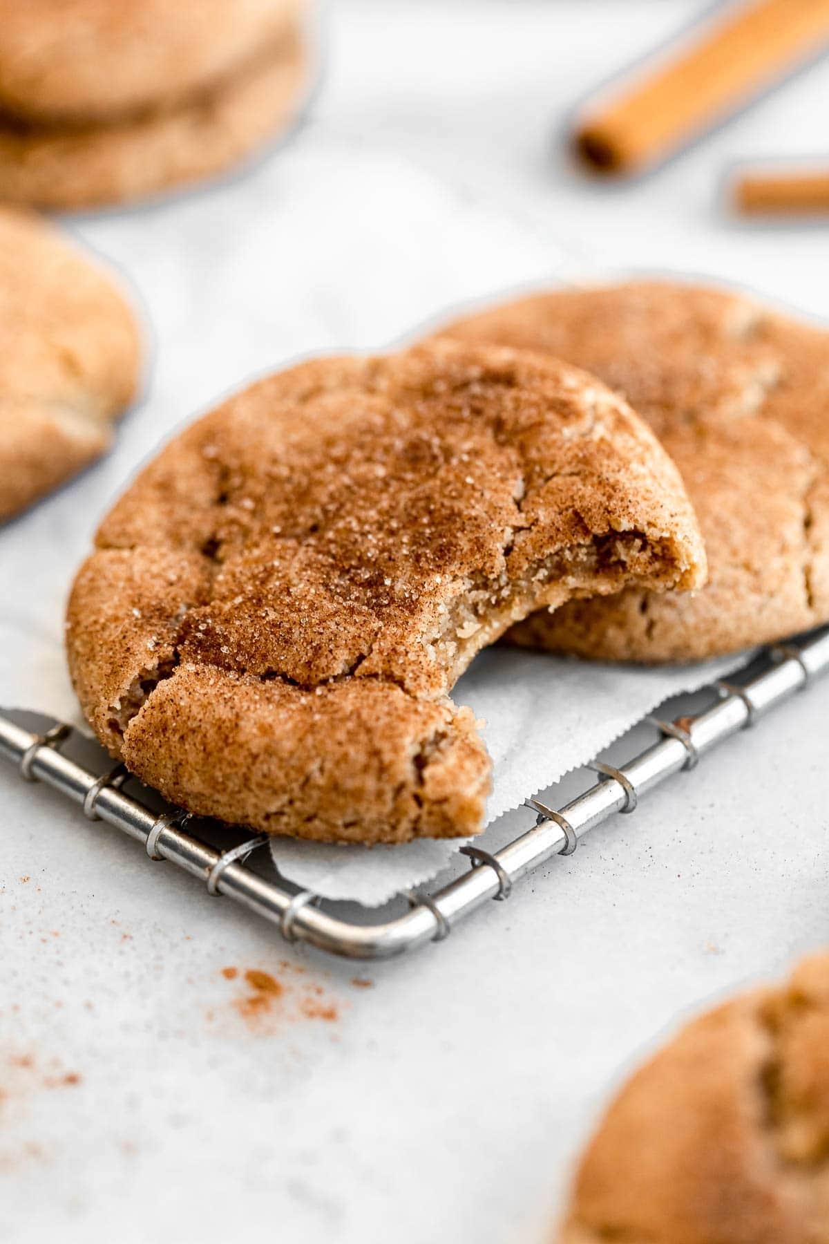 Snickerdoodle cookies coated with sugar and cinnamon powder on a cooling rack. 