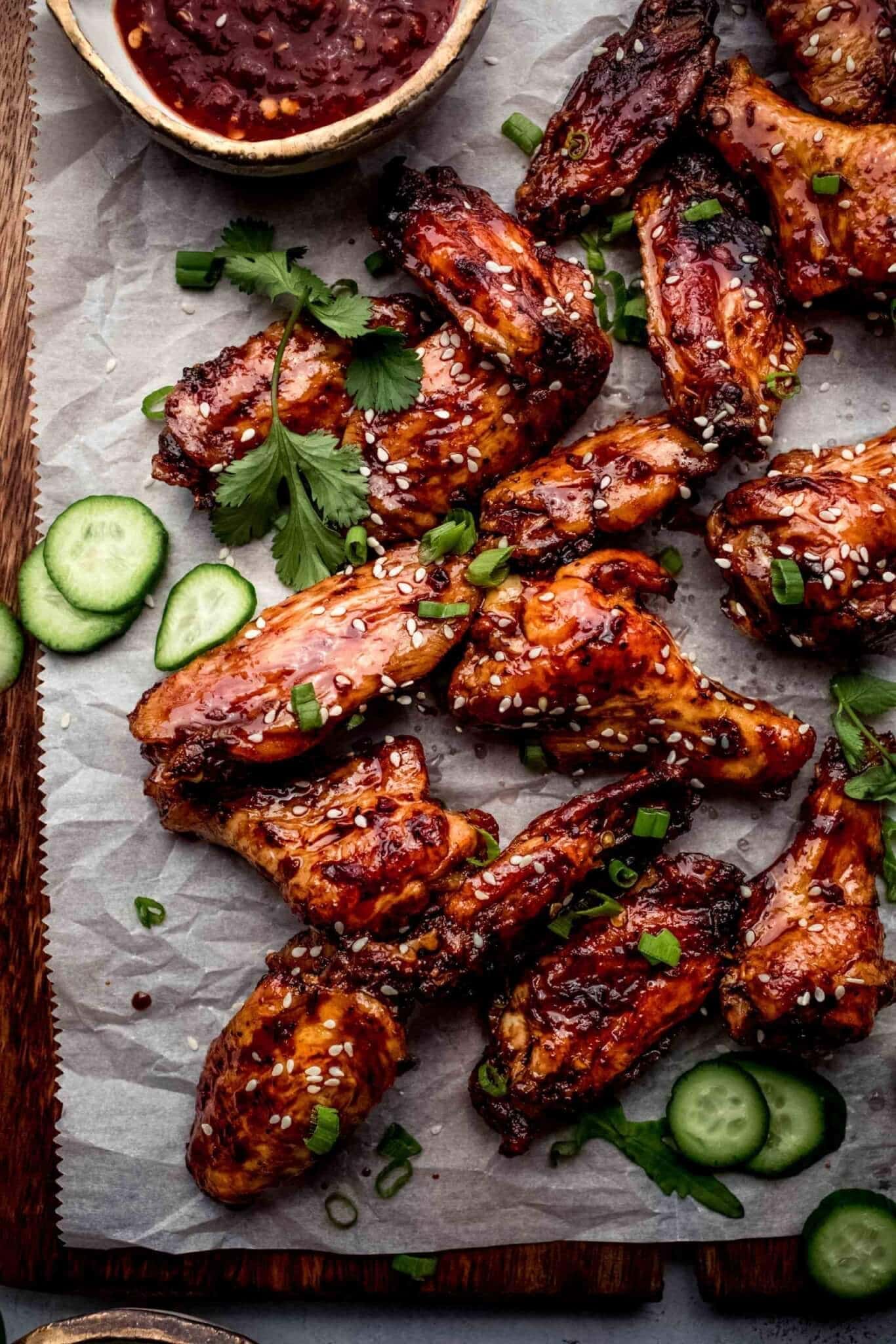 Chicken wings coated with sticky sauce garnished with sesame seeds and chopped onion leaves. 