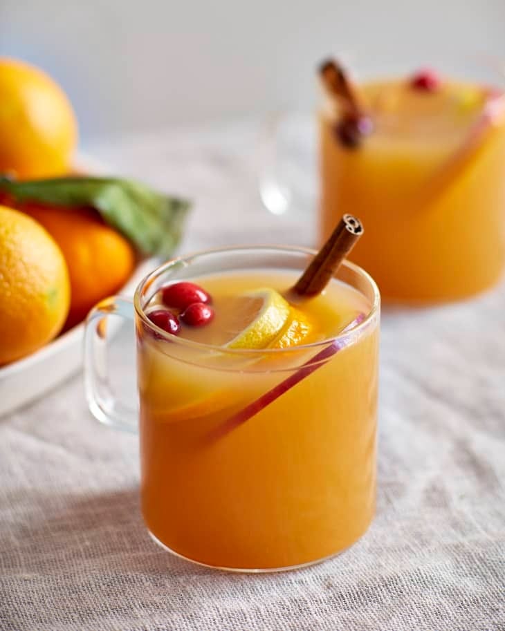 Wassail punch in glass mug garnished with orange slices, apple and cinnamon stick. 