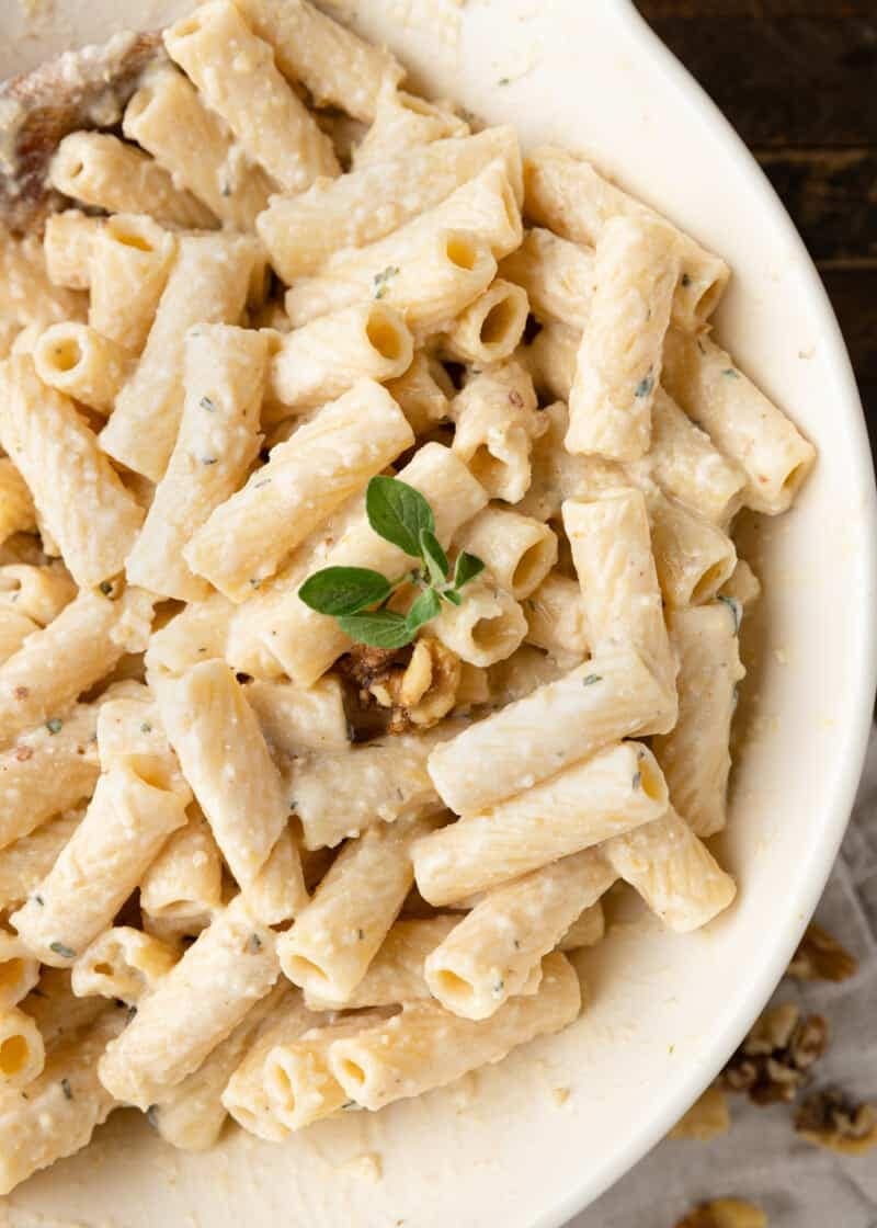 Pasta with white pesto sauce served on a white plate. 