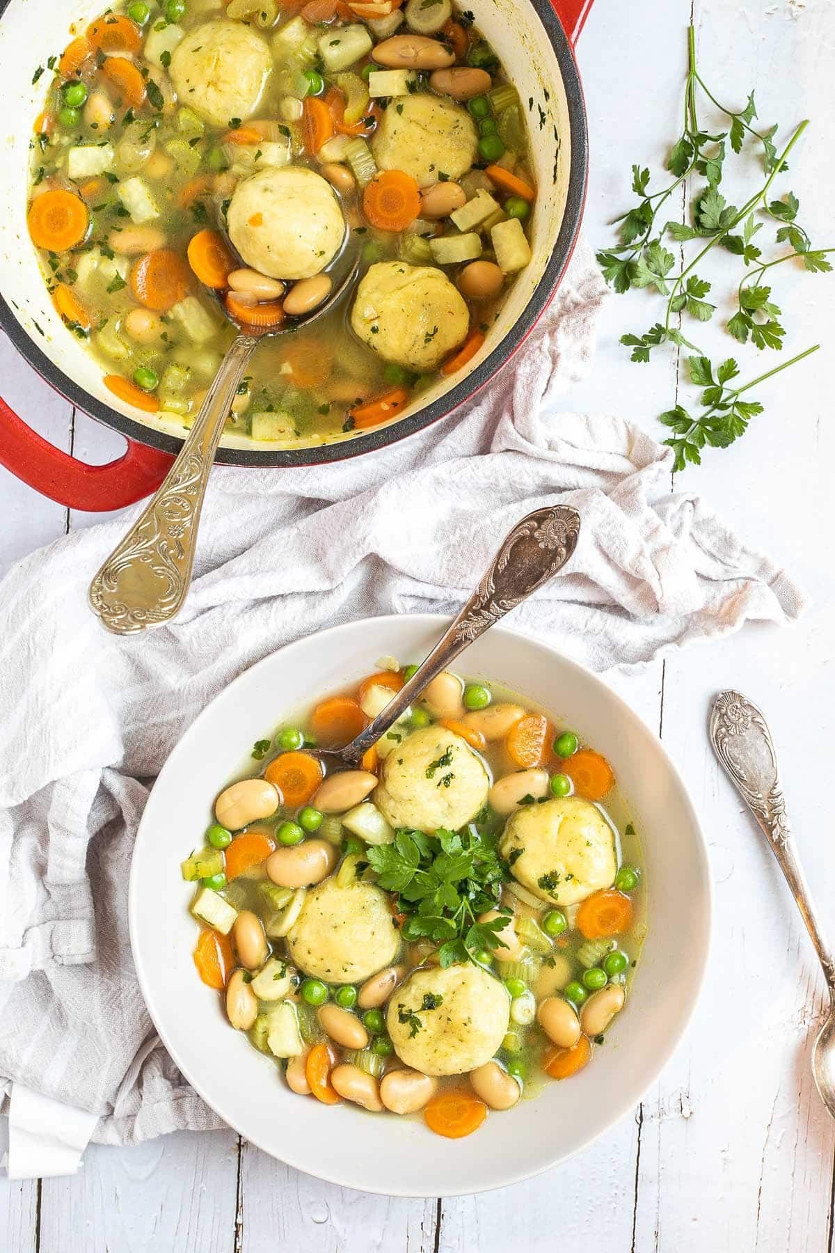 Vegan dumpling soup with peas, lima beans, celery, and carrots in a bowl with vegan dumplings- top view