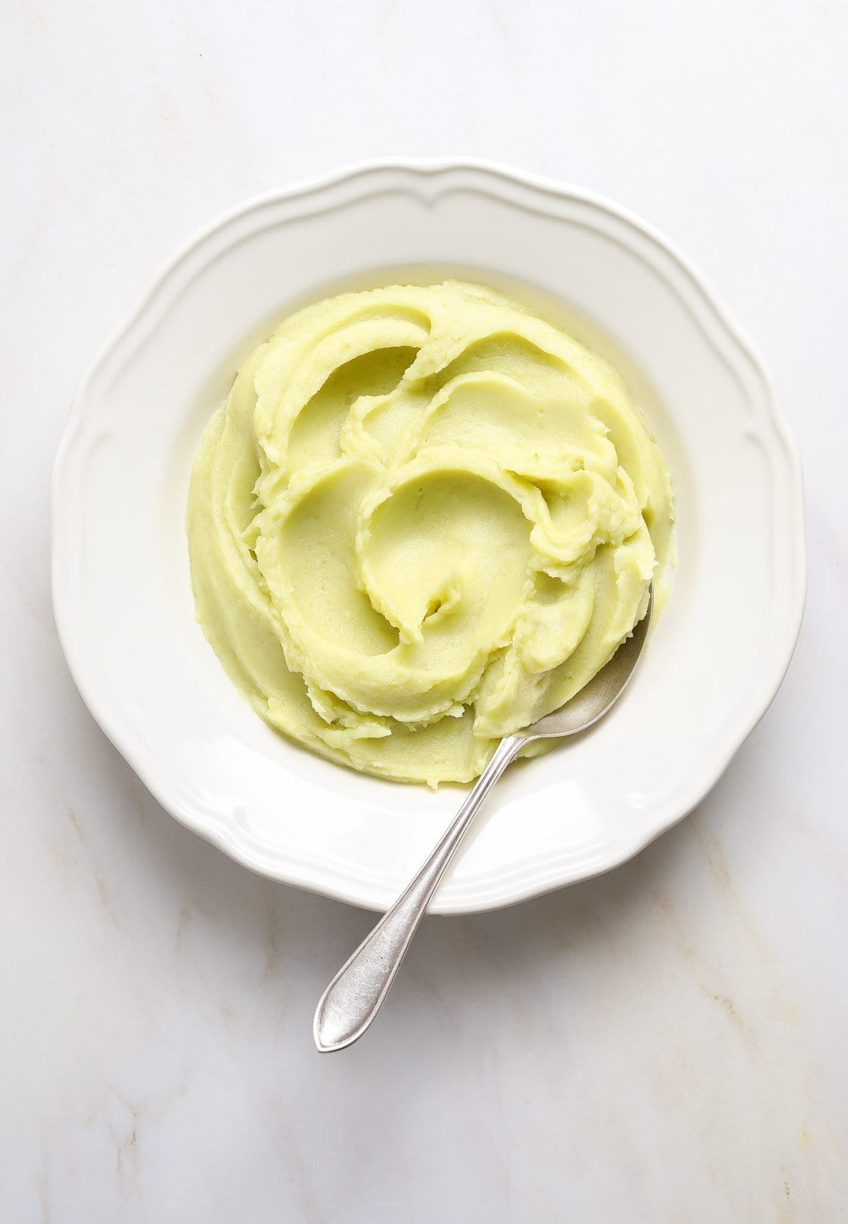 Creamy whipped japanese sweet potatoes on a plate with a spoon- top view