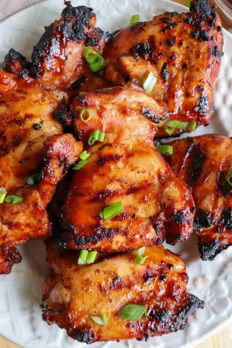 Grilled marinated chicken thighs served on a plate garnished with chopped parsley.