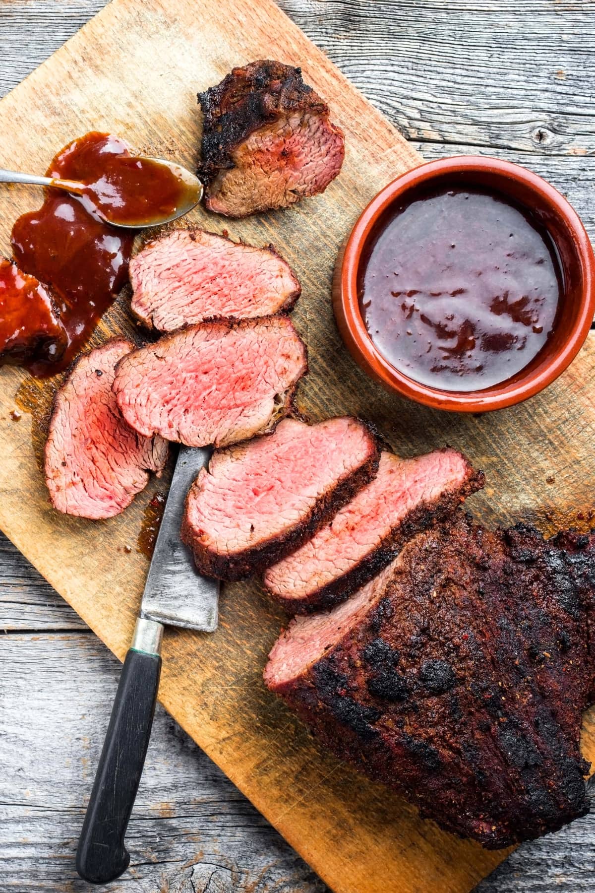 Homemade tri tip steak with barbecue sauce on a wooden board