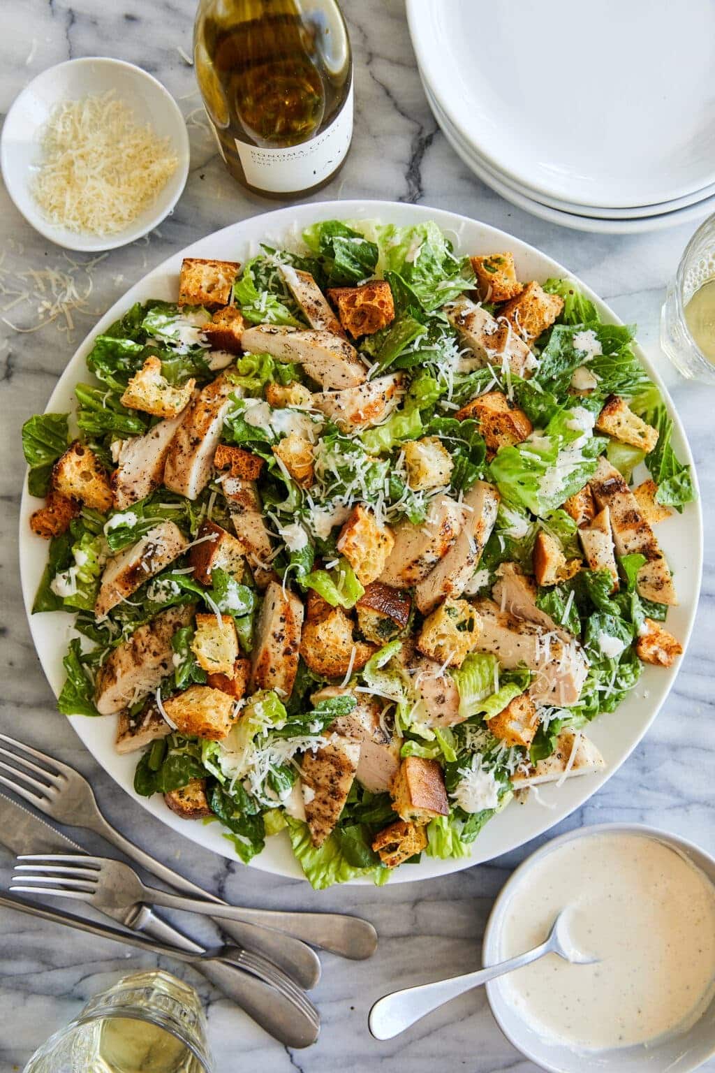 A plate of Caesar salad with romaine lettuce, Parmesan shavings, and seasoned croutons. 