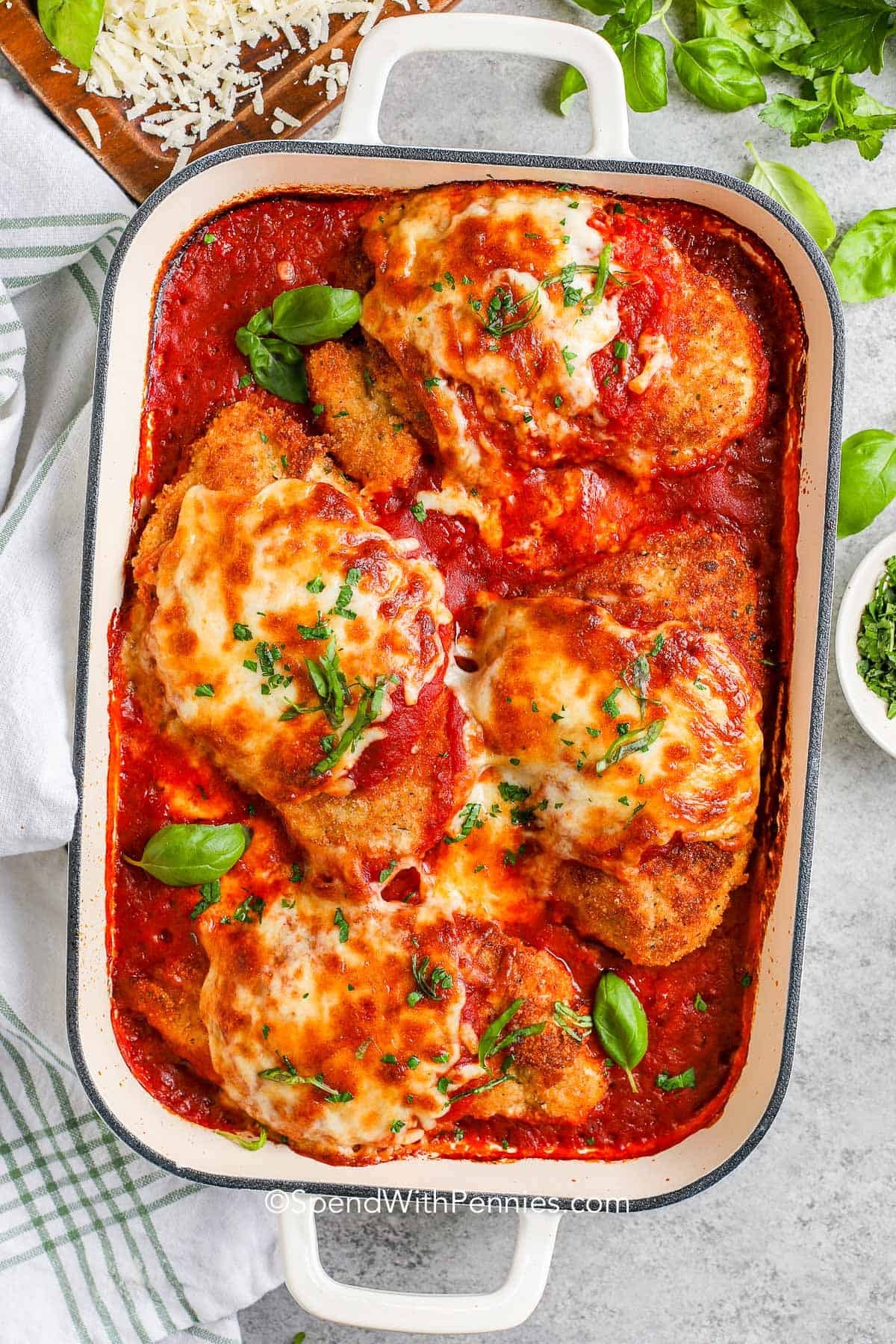 Baked breaded chicken smothered in marinara and melted cheese on a casserole dish. 