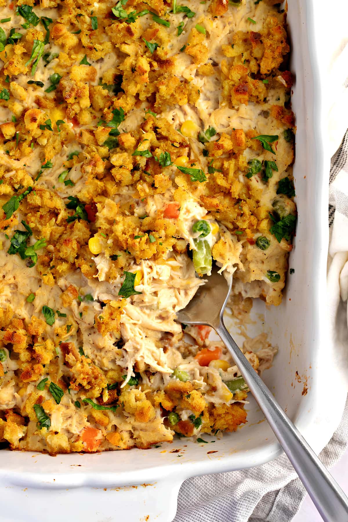 Chicken stuffing with crumbly toppings casserole on a dish with spoon. 