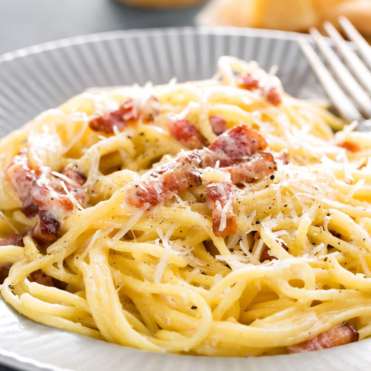 Pasta carbonara in a plate with cheese and bacon bits.