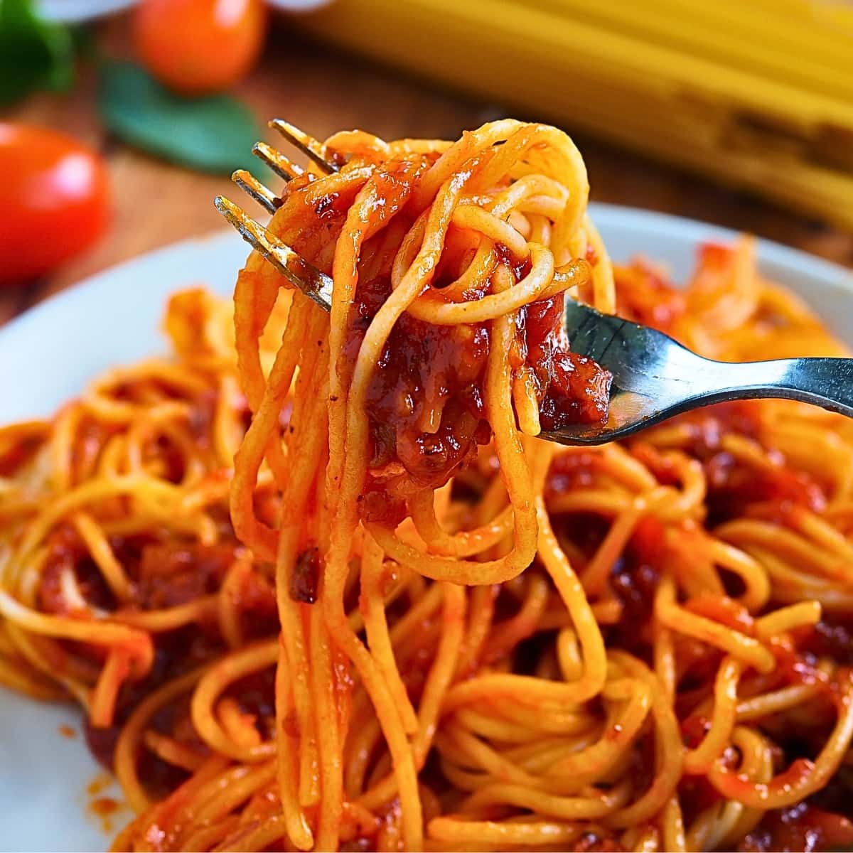 Fork picking meaty spaghetti served on a plate. 