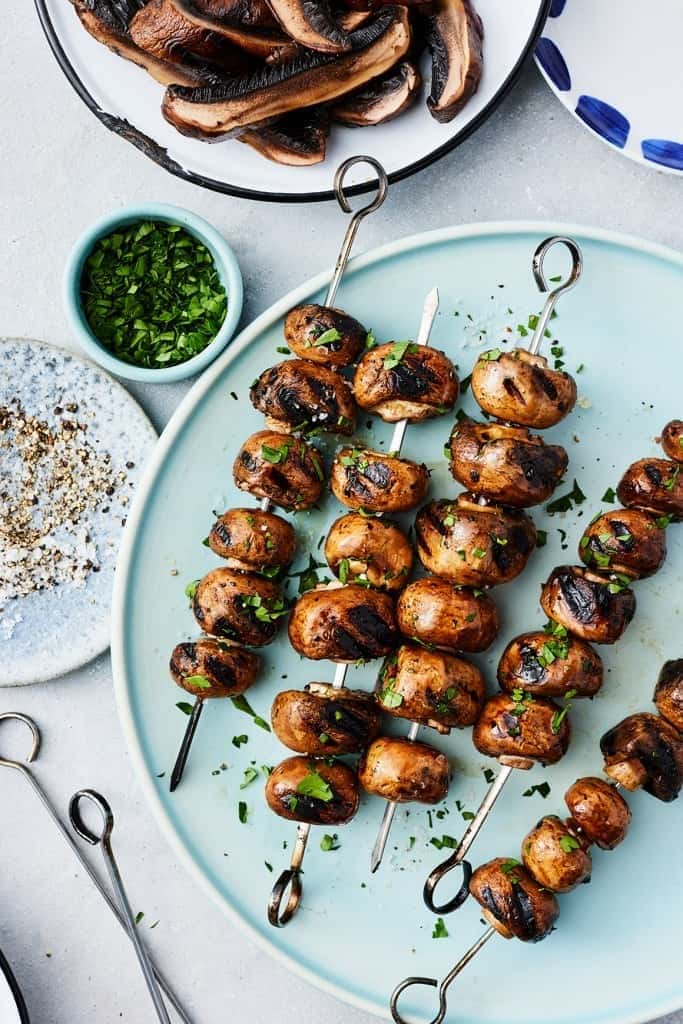 Grilled mushrooms on skewers served in plate. 