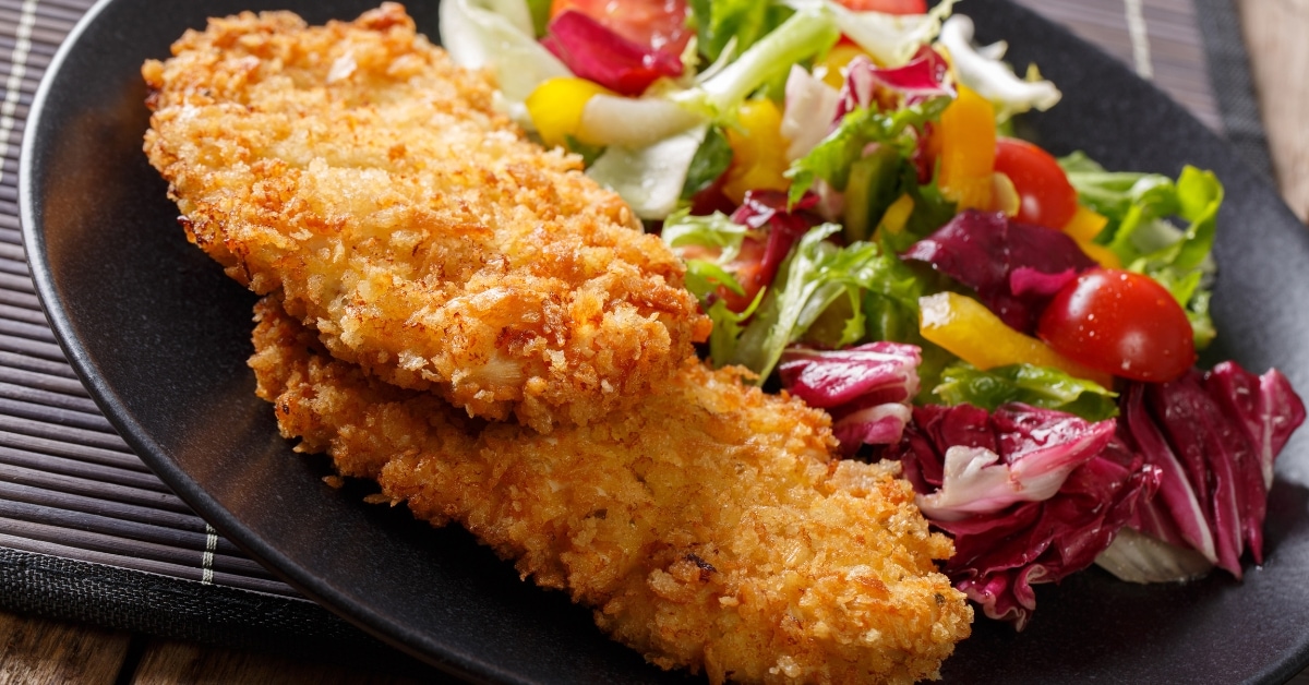 Pork schnitzel served with healthy vegetables in a black plate