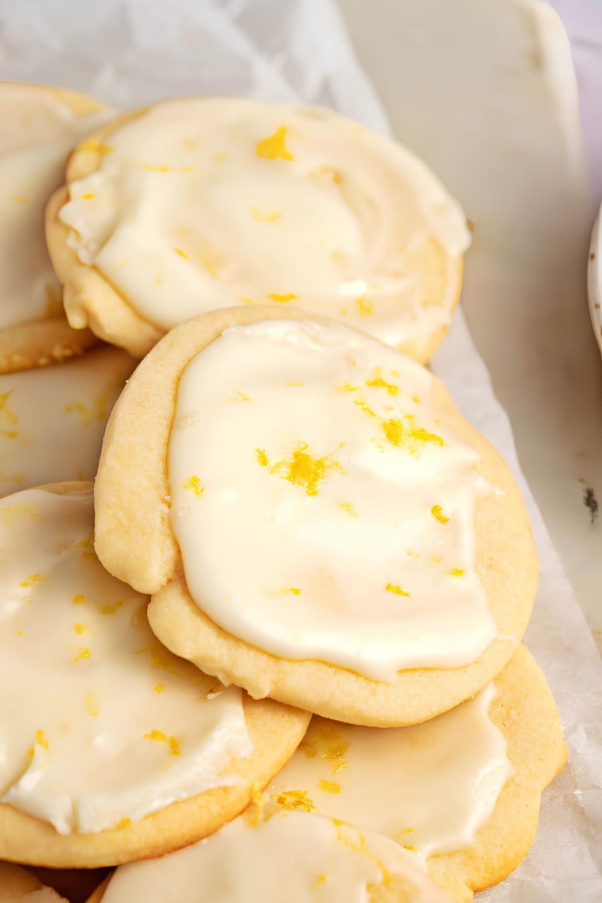 Round lemon shortbread cookies dipped in homemade lemon glaze garnished with lemon zest.