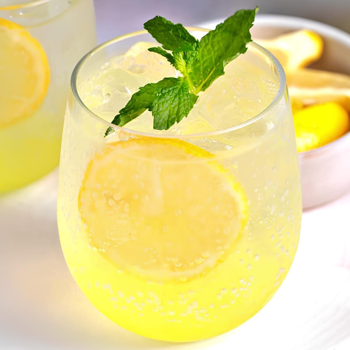 Ice cold limoncello spritz cocktail on glass with lemon slices and fresh mint leaves garnish. 