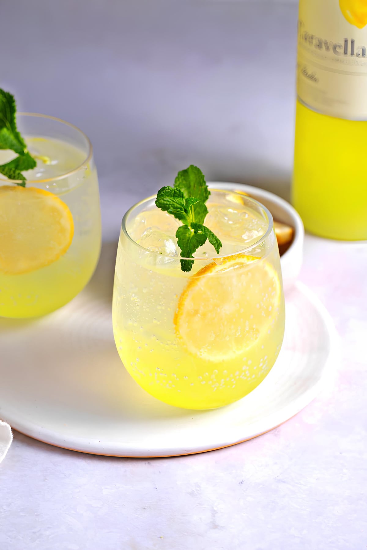 Limoncello spritz cocktail on glasses garnished with lemon wheel. 
