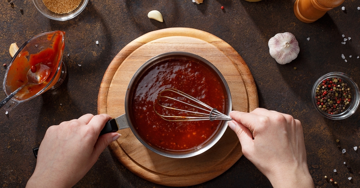 Woman mixing sauce in a pan with spices and ingredients