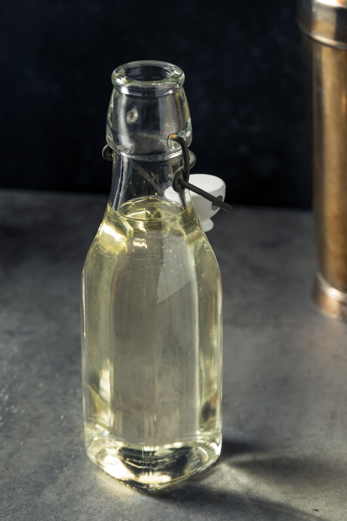 Glass bottle with simple syrup on a concrete table.