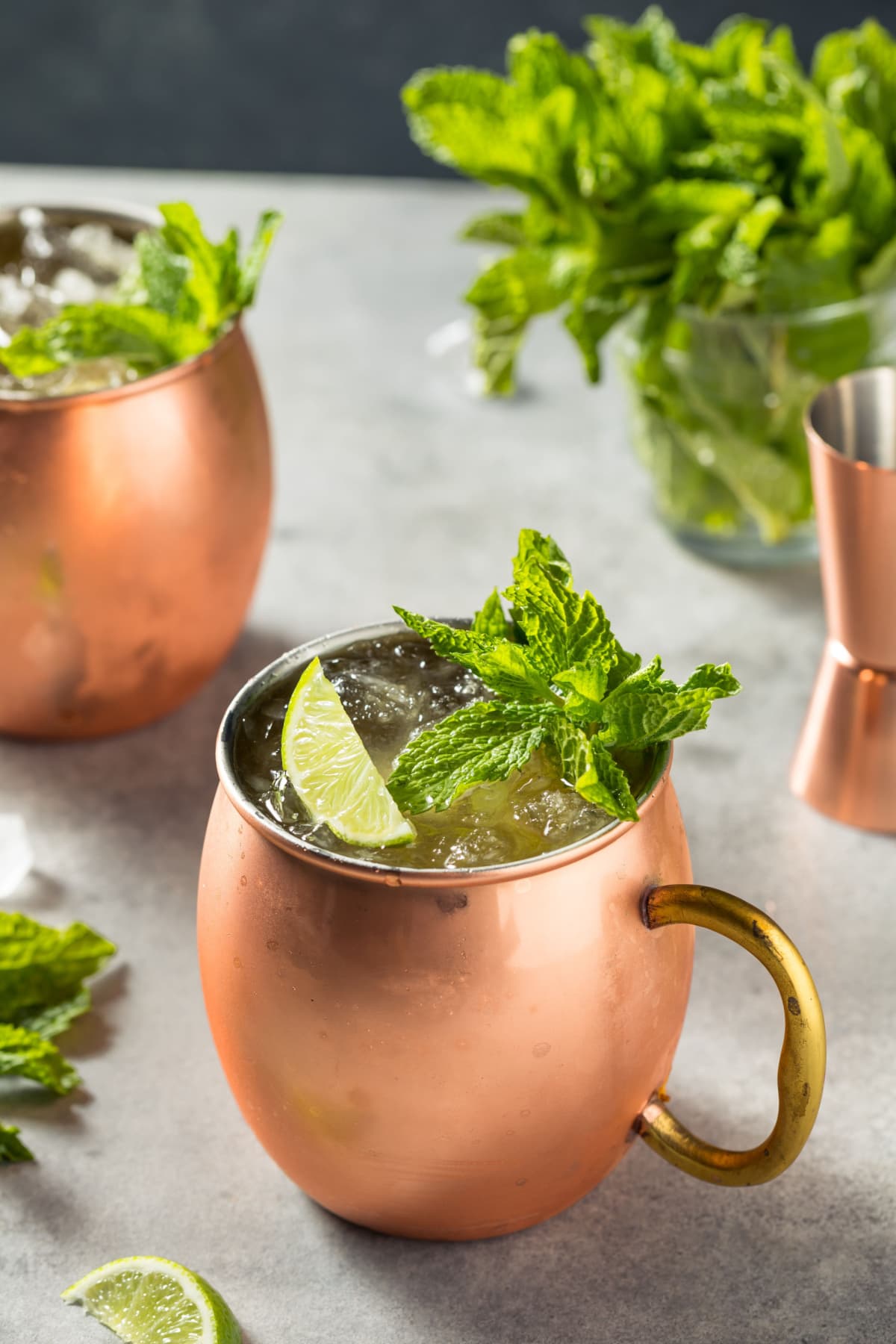 Two servings of Kentucky mule in a mule mug beside a bunch of mint sprig in a glass.