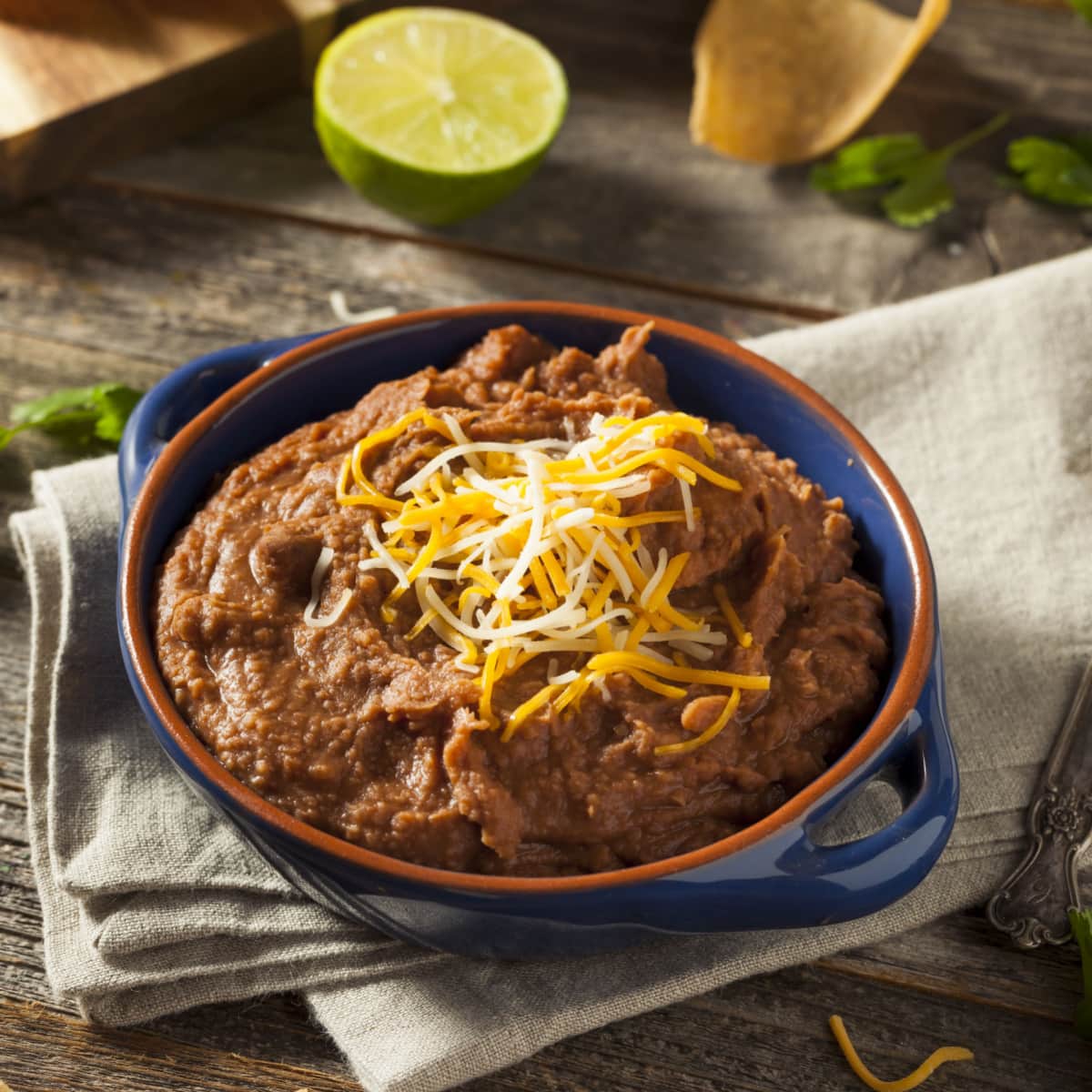 Mashed refried beans on a blue pot topped with grated cheese.