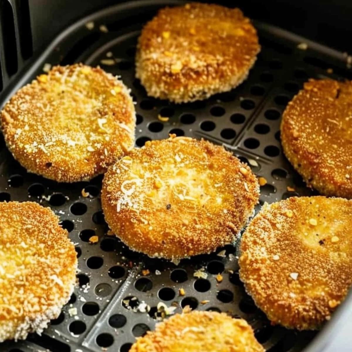 Breaded green tomatoes inside an air fryer.