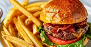 Burger with oven baked potatoes served with fries on a plate.