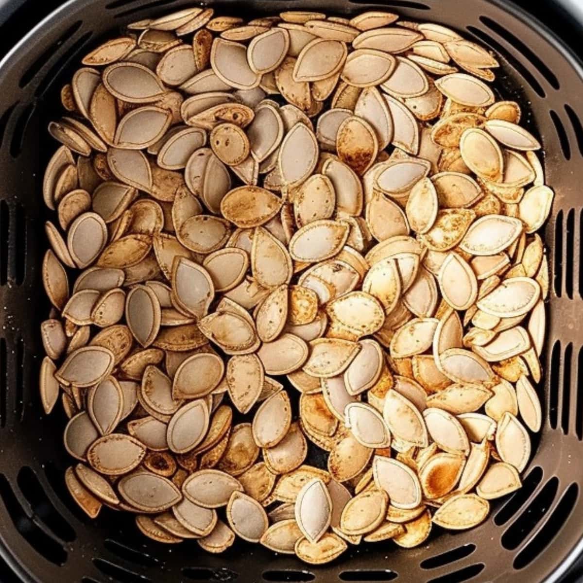 Pumpkin seeds inside an air fryer basket.