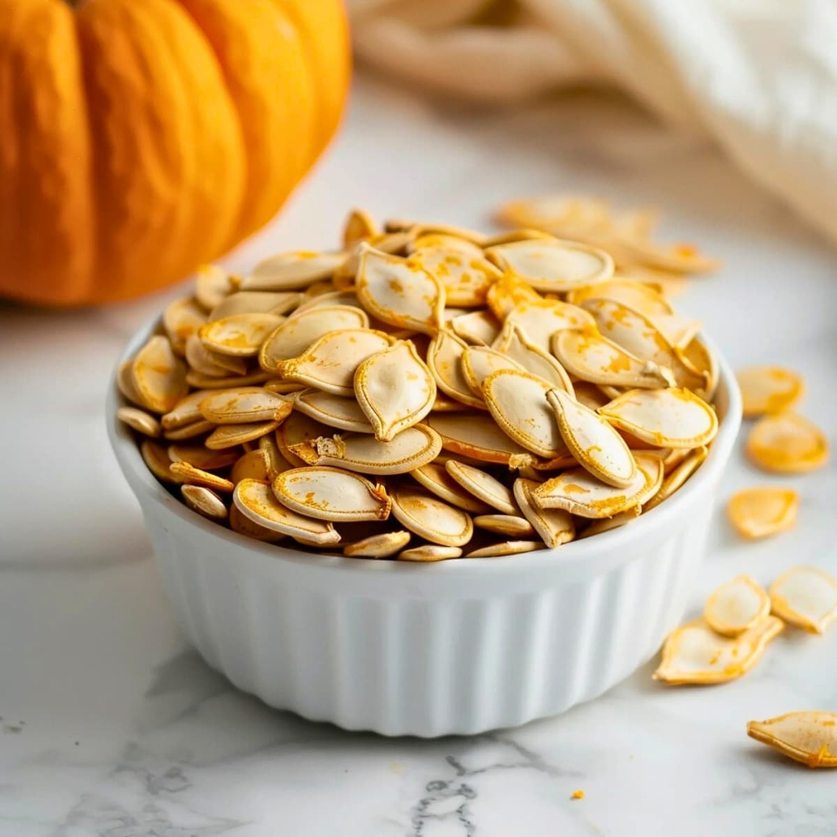 Pumpkin seeds in a white bowl.