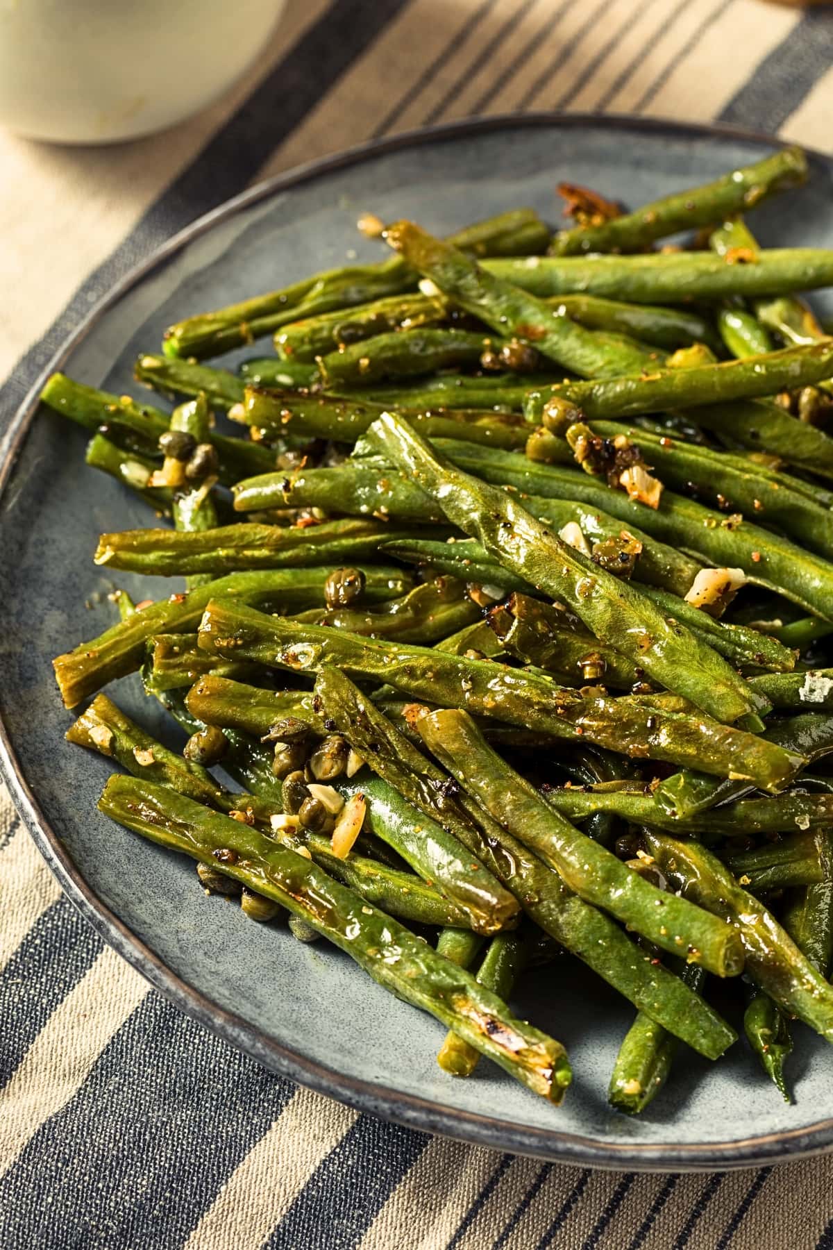 Roasted green beans on a gray plate with garlic. 