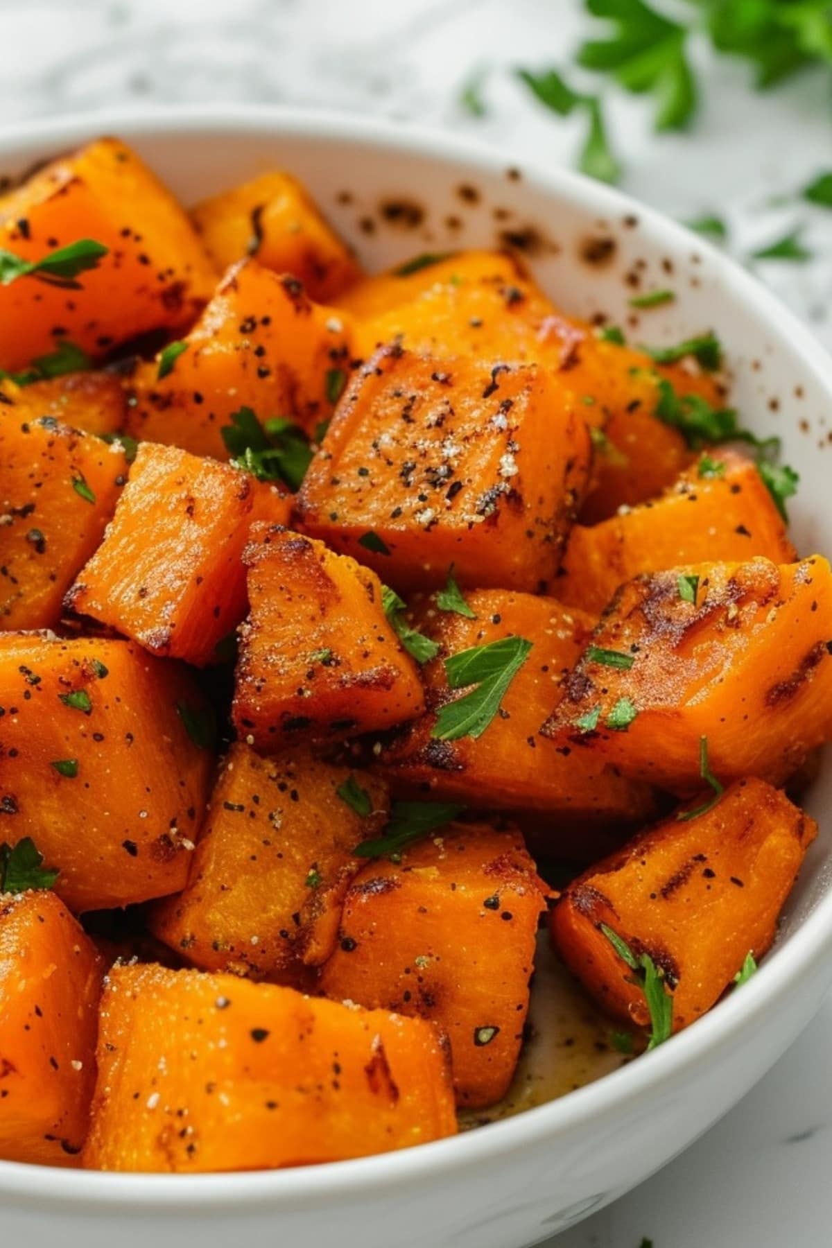 Seasoned air fryer butternut squash in a white bowl.