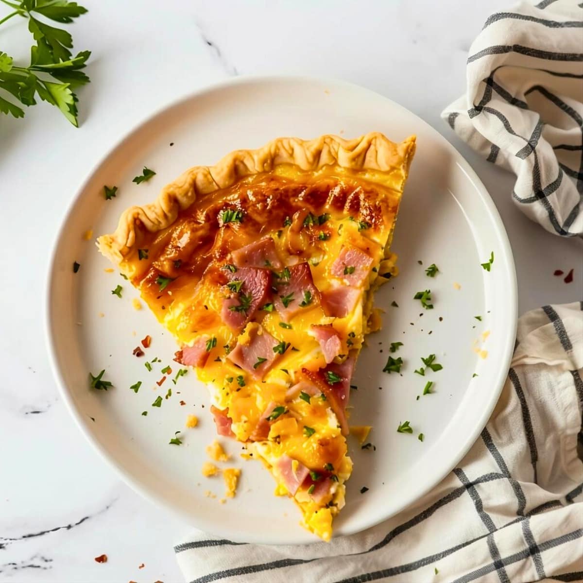 Top view of a slice of ham and cheese quiche in a plate