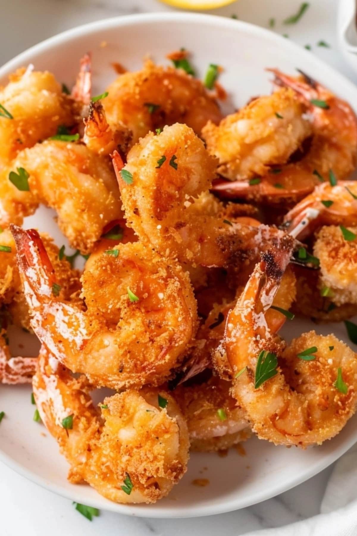 Bunch of breaded shrimp in a white plate.