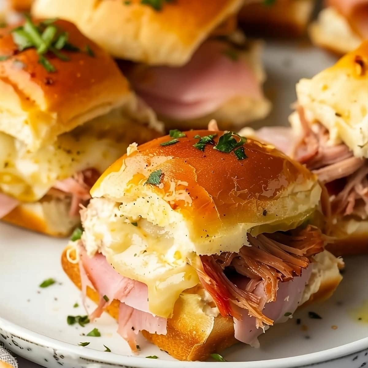 Cuban sliders served on a white plate garnished with chopped parsley.