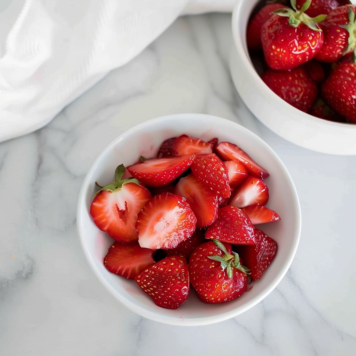 A bowl of fresh strawberries on a white marble table