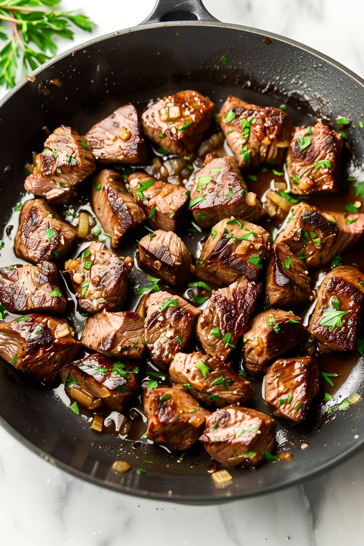 Garlic butter steak bites in a black skillet with parsley