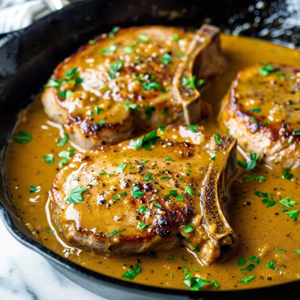 Porkchops with honey mustard sauce in skillet.