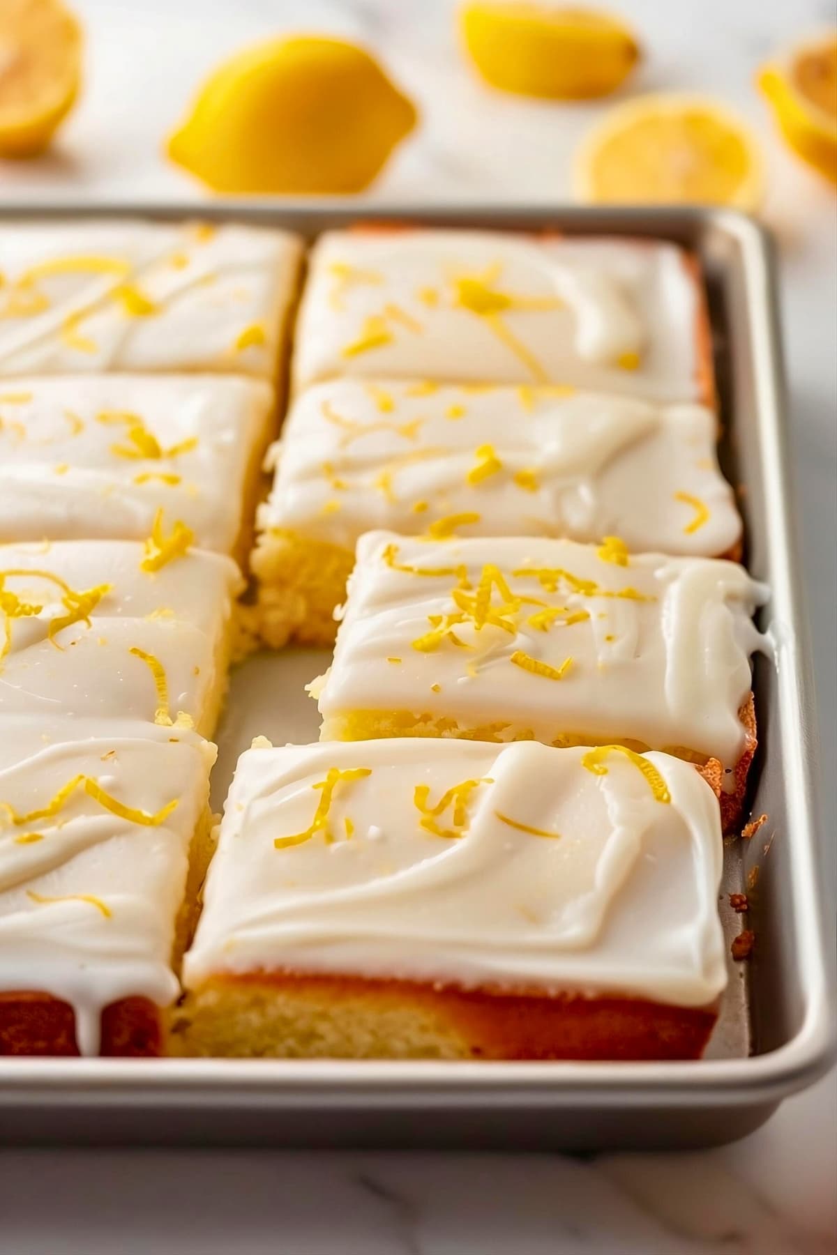 Lemon sheet cake sliced in a baking pan.