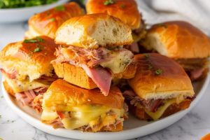 Bunch of pulled apart sliders with cheese stack on a plate.