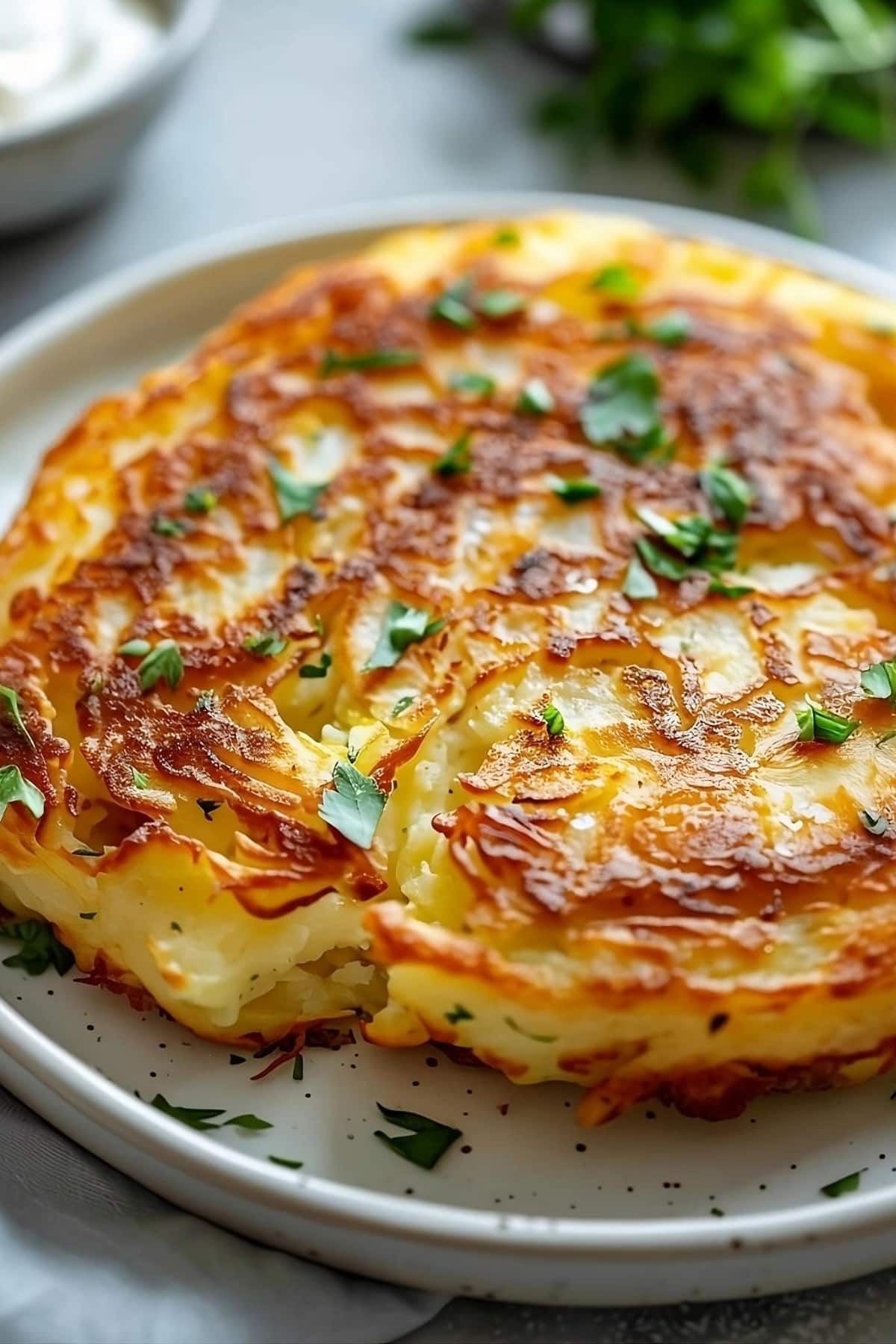 Whole bubble and squeak on a plate garnished with chopped parsley leaves.