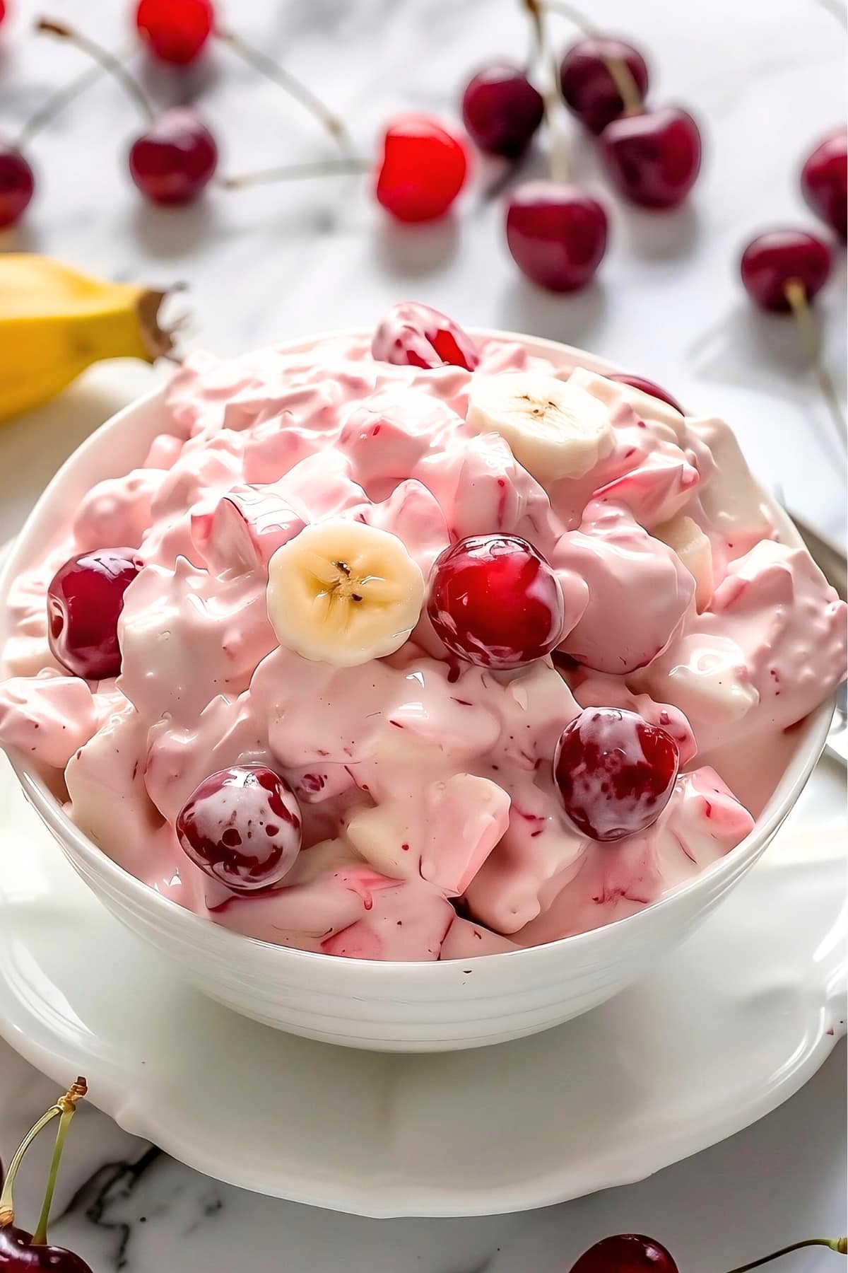 Creamy better than sex fruit salad garnished with banana slices and cherries.