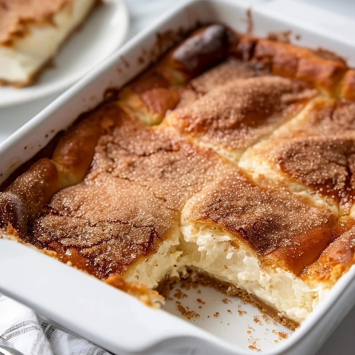 Cheesecake crescent rolls in a baking dish, slice missing.