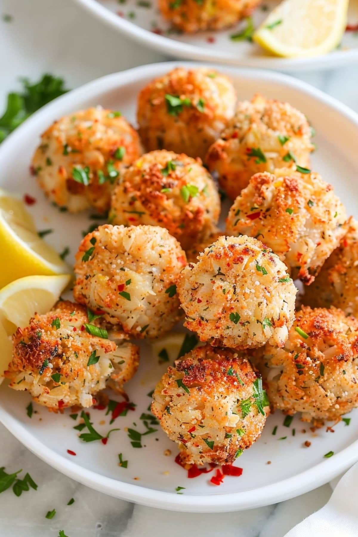 Closeup of crab balls in a white plate garnished with chopped parsley.