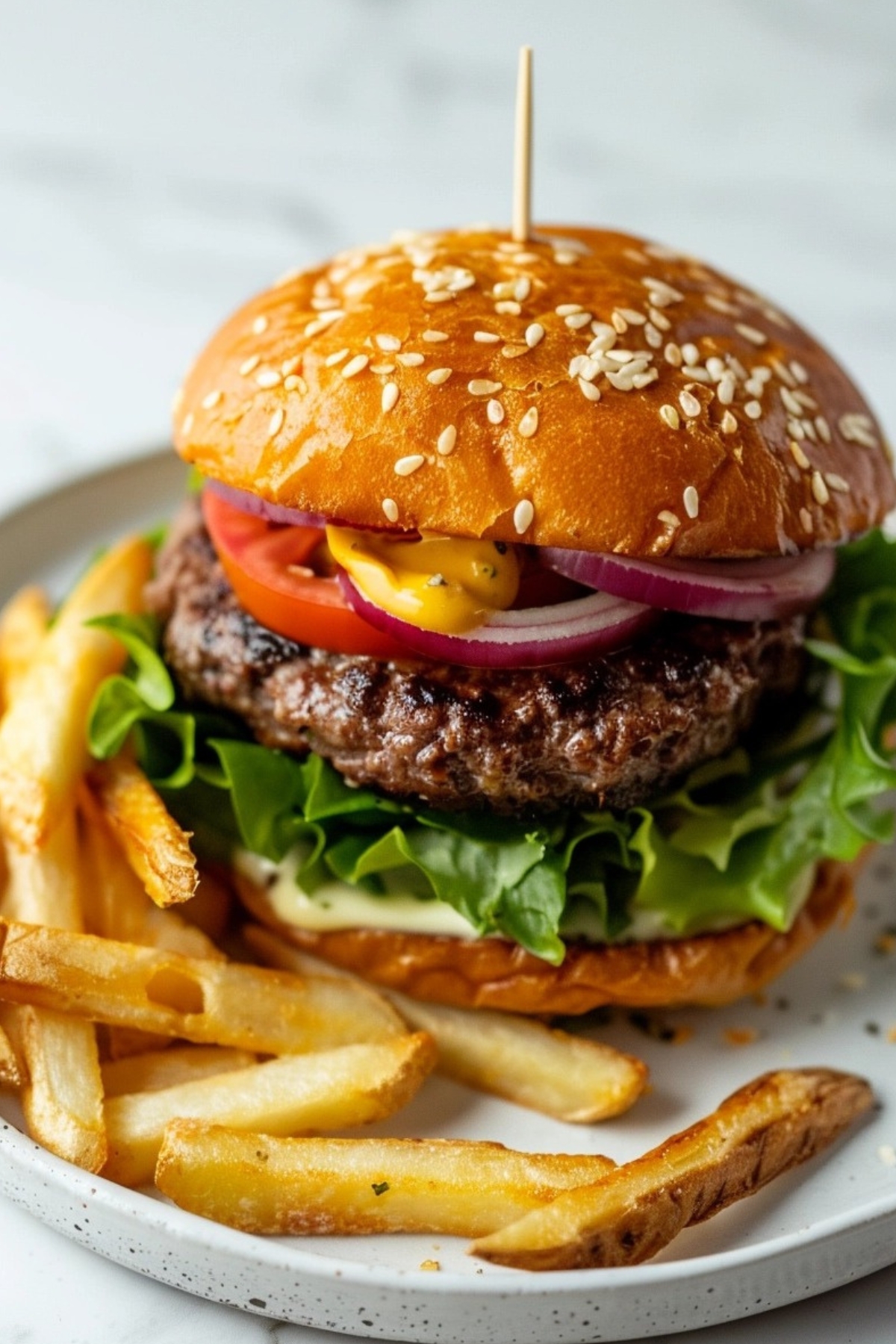 Crack burger on a white plate with fries on the side.