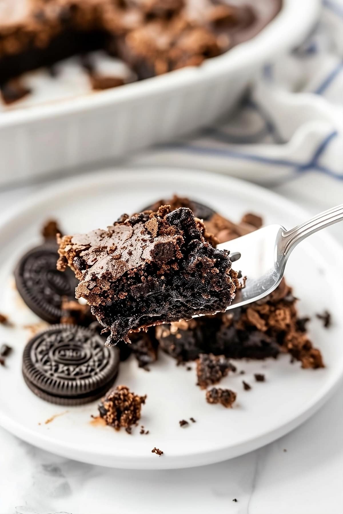 Fork with a slice of Oreo dump cake in a white plate.