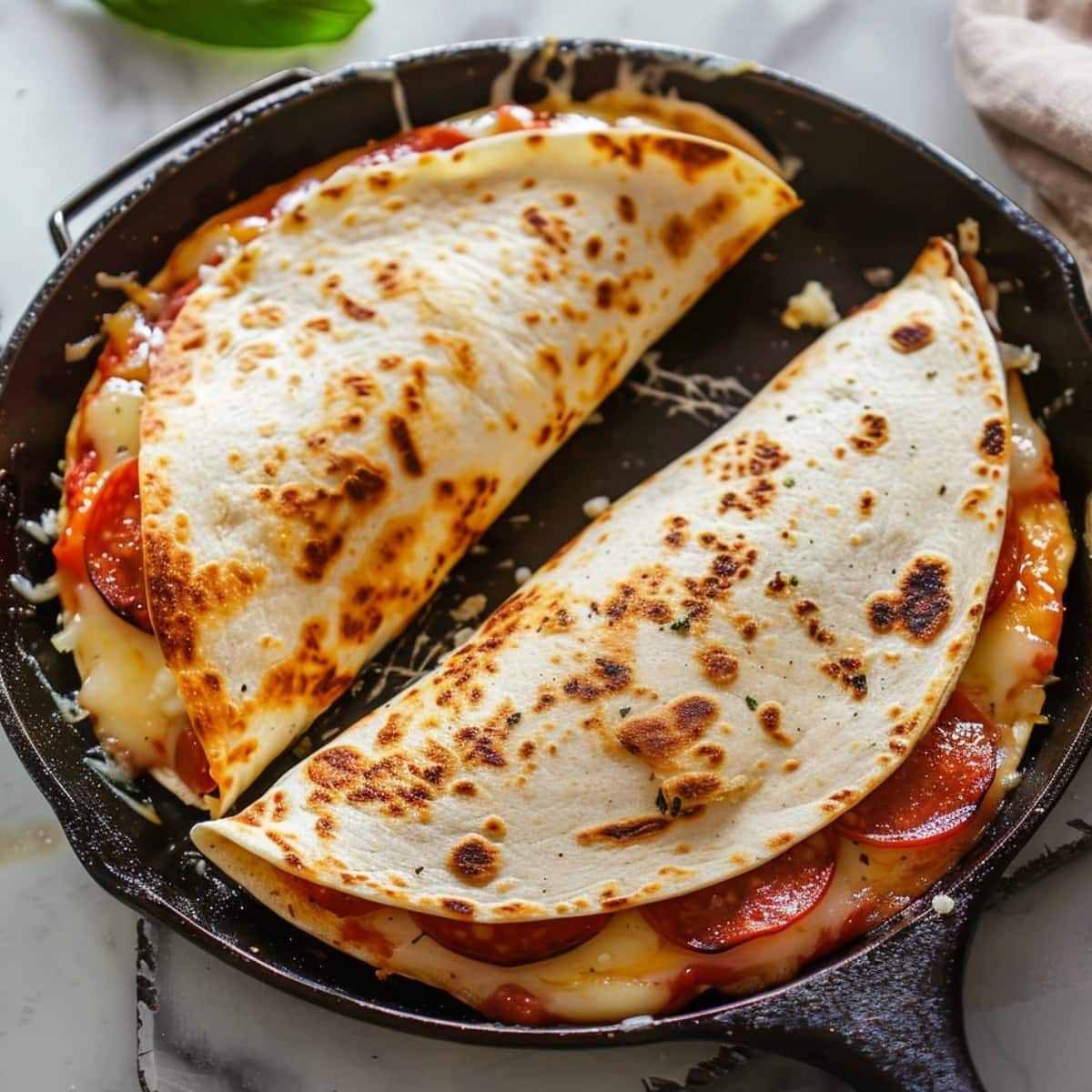 Pizza quesadilla folded in half in a cast iron skillet.