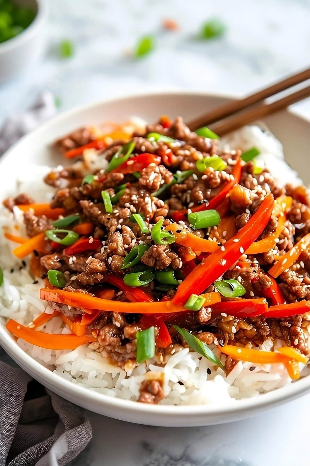 Korean beef bowl with thinly sliced carrots, red bell pepper and onions.