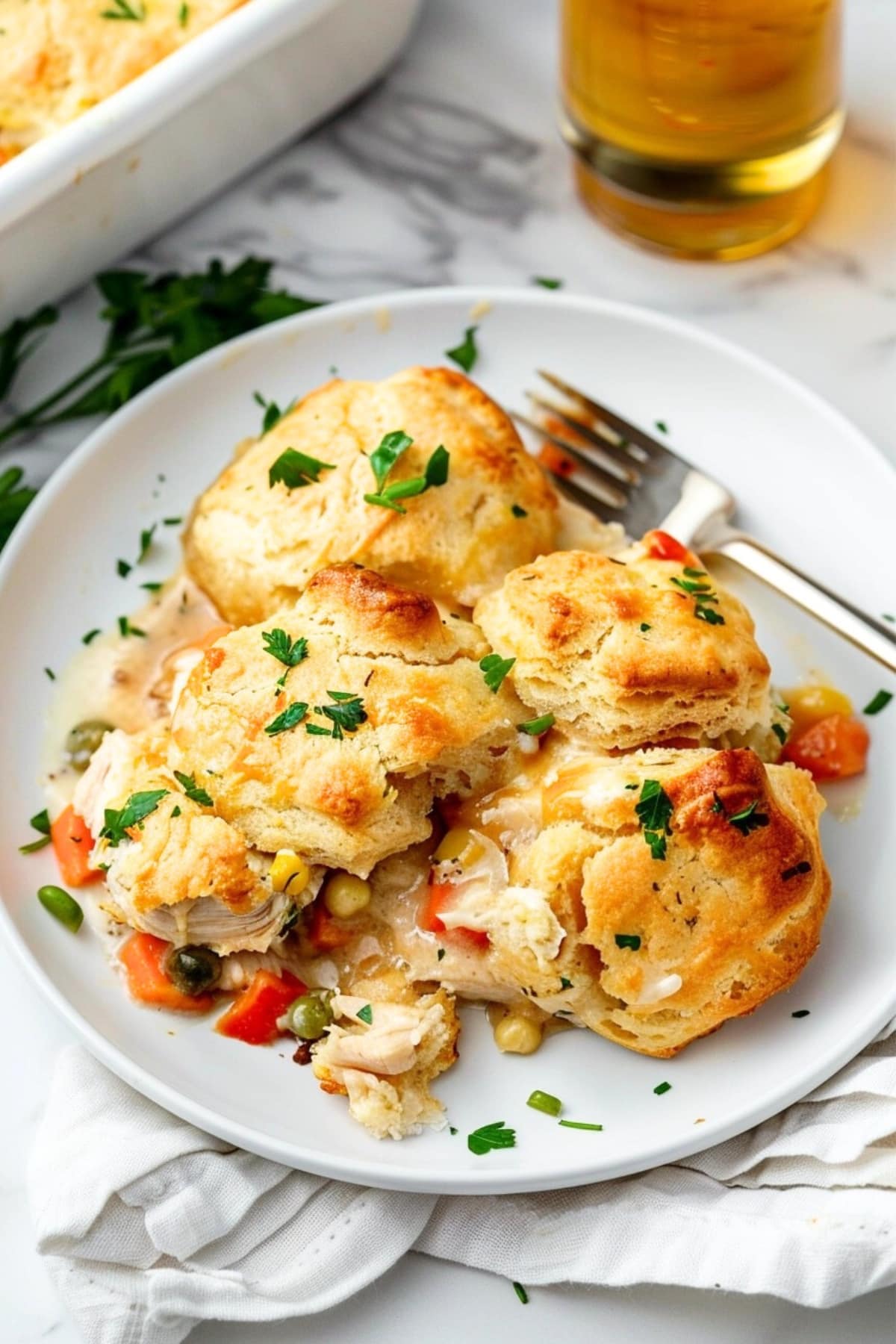 A serving of chicken and biscuit casserole on a white plate with fork.